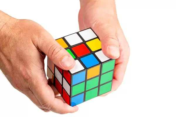 Men's hands hold a Rubik's cube on a white background