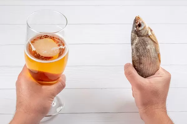 Men's hands with beer and dried fish
