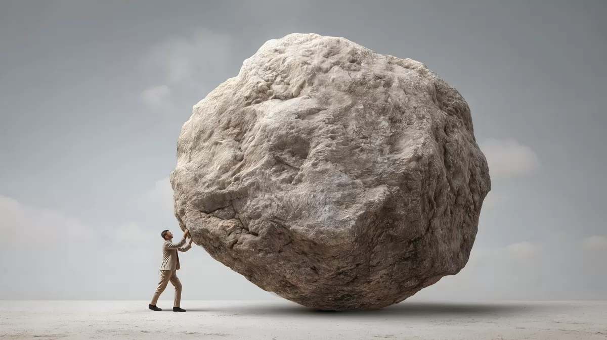 Mensch gegen gewaltigen Felsbrocken - Symbol für Herausforderung