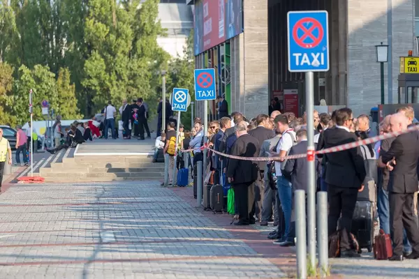 Menschen am Messegelände warten auf Taxis