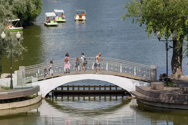 Menschen auf kleiner Brücke schauen Leuten in Tretbooten zu