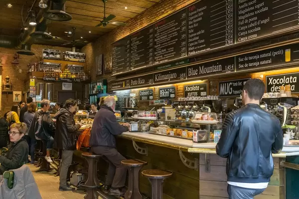 Menschen im Café mit Bäckerei-Theke im Altbaustil in Barcelona, Spanien