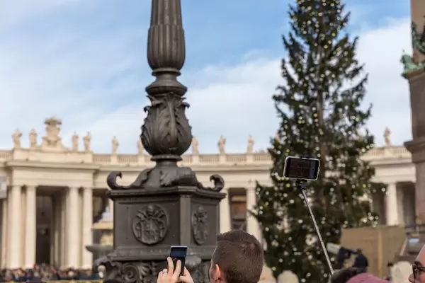 Menschen machen Fotos vom Angelus auf dem Peterplatz im Vatikan