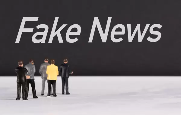 Menschen stehen vor dem Text "Fake News / Falschnachrichten"