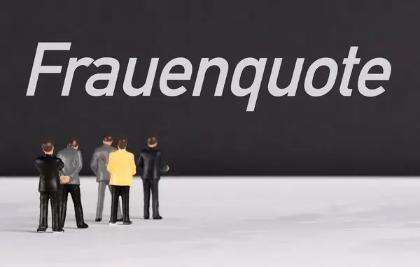 Menschen stehen vor dem Text "Frauenquote"