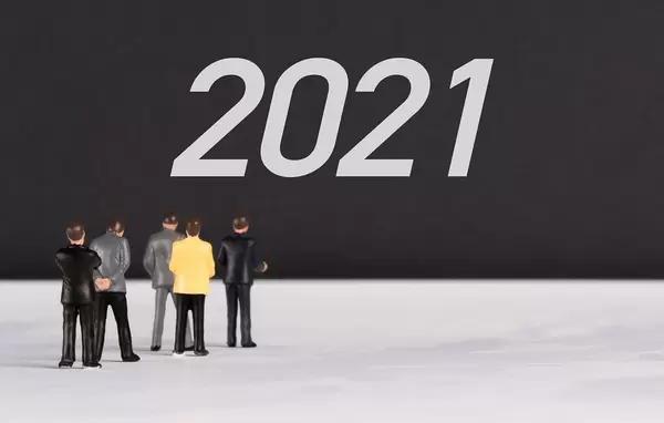 Menschenfiguren stehen vor einer Wand mit  "2021" als Text