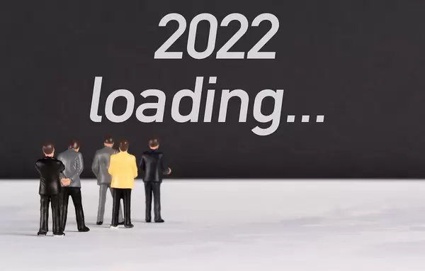 Menschenfiguren stehen vor einer Wand mit  "2022 loading" als Text