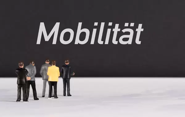 Menschenfiguren stehen vor einer Wand mit  "Mobilität" als Text