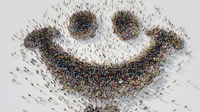 Menschenmenge formt lachendes Smileymotiv aus Vogelperspektive