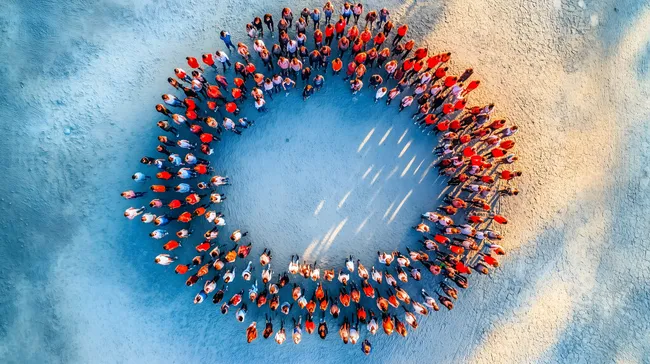 Menschenmenge in Kreisform auf Sandstrand