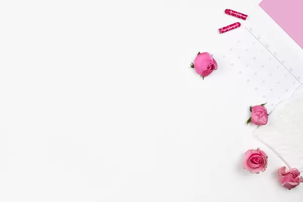 Menstrual cycle calendar: white background with copy space, roses, panty liners and tampons