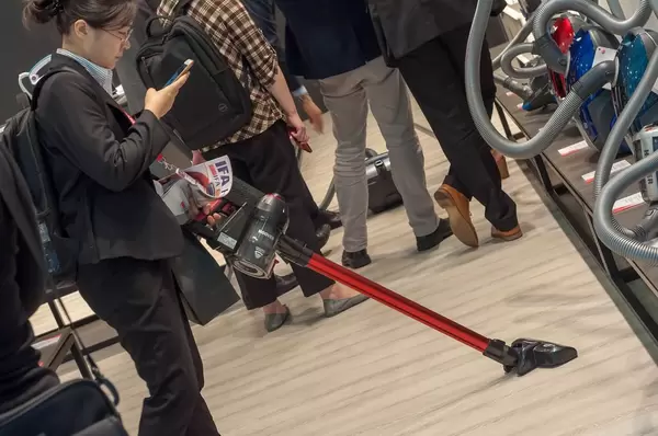 Messebesucherin mit einem Akku-Handsauger von Hoover