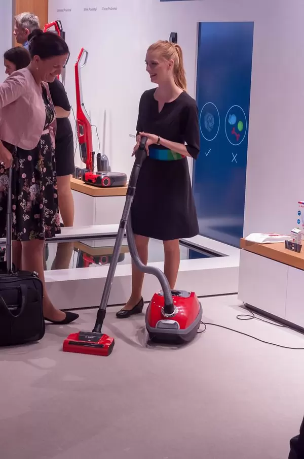 Messehostess führt einen Staubsauger von Bosch vor