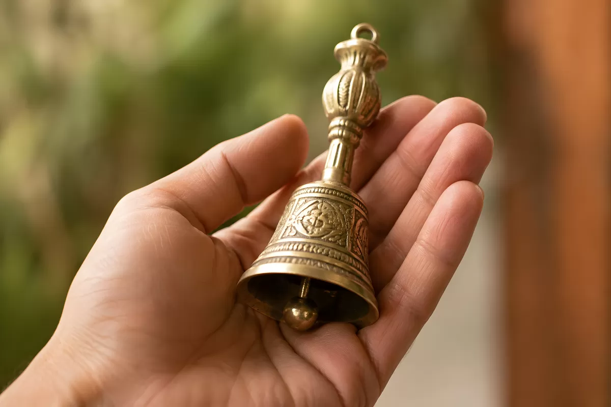 Messingklingel mit Ornamenten liegt in einer Hand