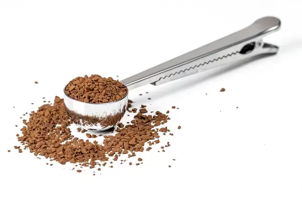 Messlöffel mit Pulverkaffee auf weißem Hintergrund