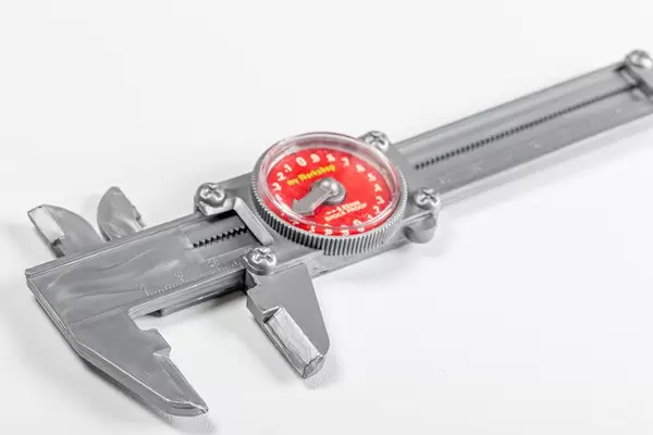 Messschieber aus Plastik als Kinderspielzeug, vor weißem Hintergrund