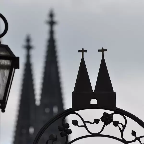 Metal gate with decoration inspired by the profile of the cathedral in Cologne, with the cathedral itself in the background