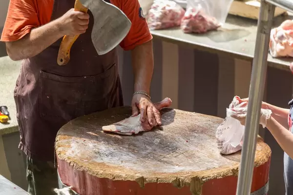 Metzger schneidet Putenkeule mit einer Axt