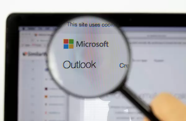 Microsoft-Logo am PC-Monitor, durch eine Lupe fotografiert