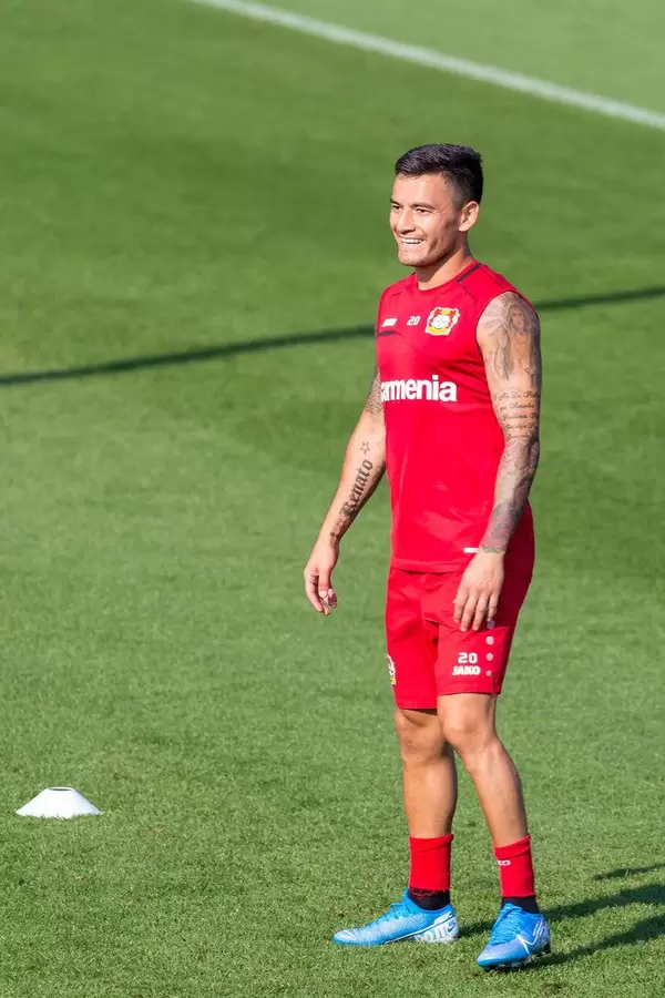 Midfielder Charles Aránguiz, with religious tattoos, laughs cheerfully during training on the football field