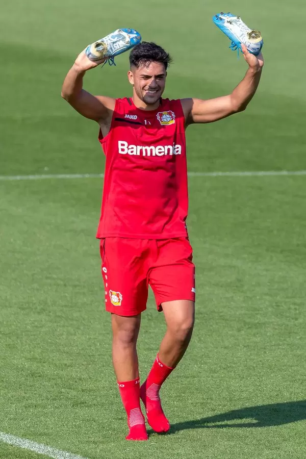 Midfielder Nadiem Amiri after training, laughing while holding up his blue football shoes