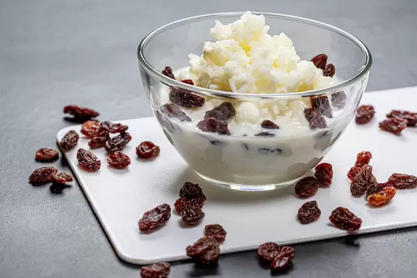 Milchreis mit Rosinen in einer Glasschale auf schwarzem Hintergrund