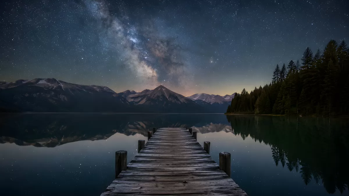 Milchstraße über Bergsee mit Holzsteg bei Nacht