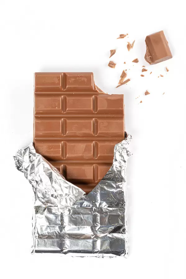 Milk chocolate bar with broken pieces on white, top view