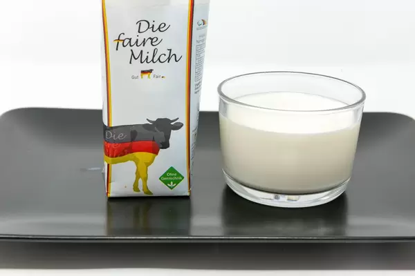 Milk Made in Germany - Fair Milk - not genetically modified - Milk in a glas with packaging on white plate