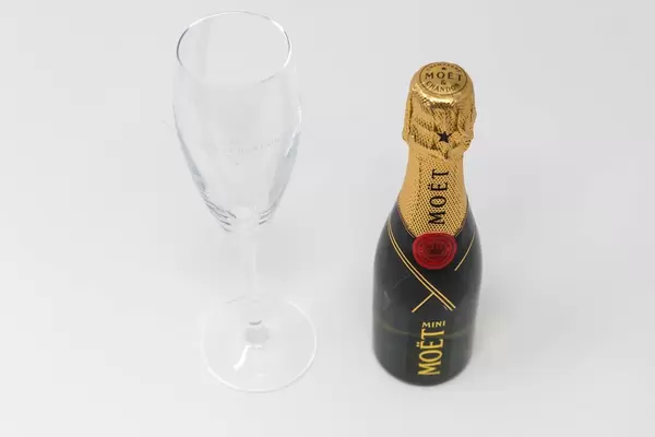 Mini Moët Flasche mit leerem Champagnerglas auf weißem Hintergrund