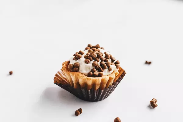 Mini-Törtchen mit Sahne und Schoko-Streusel vor weißem Hintergrund
