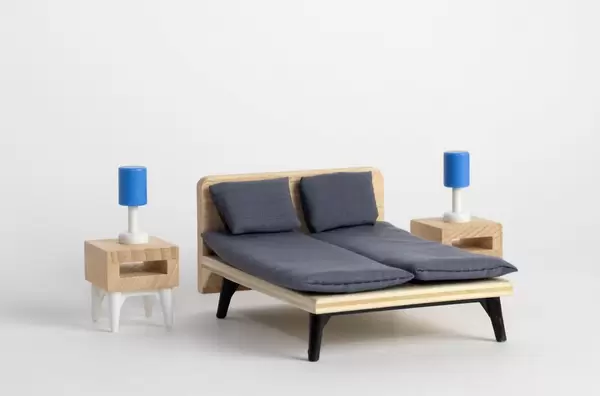 Miniatur Schlafzimmer-Ausstattung mit hölzernen Nachttischen mit blau-weißen Tischlampen und Doppelbett mit mattgrauer Kissen und schwarzer Matratzen - Nahaufnahme
