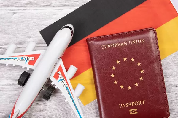 Miniature airplane and passport over flag of Germany