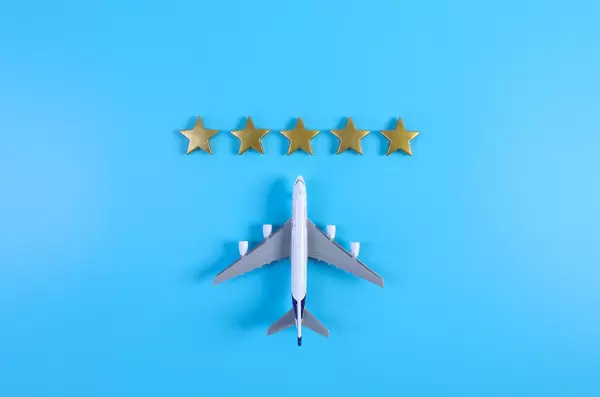 Miniature airplane with golden five golden stars on blue background