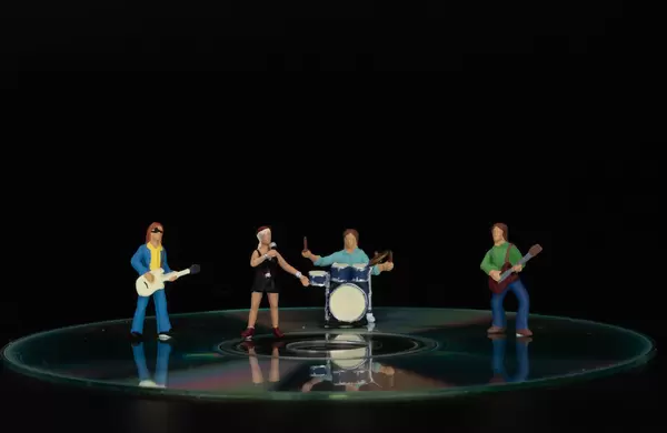 Miniature band standing on CD on black background