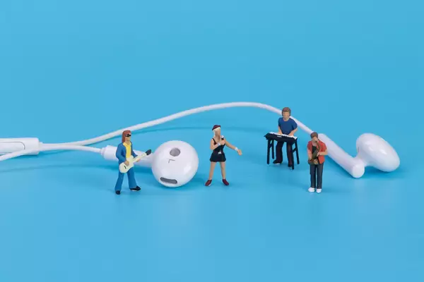 Miniature band with earbuds on blue background