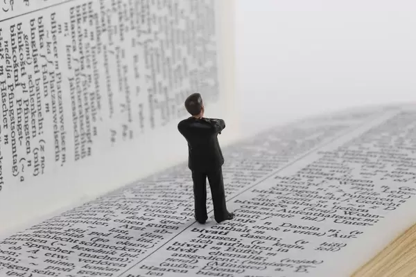 Miniature businessman figure standing on book