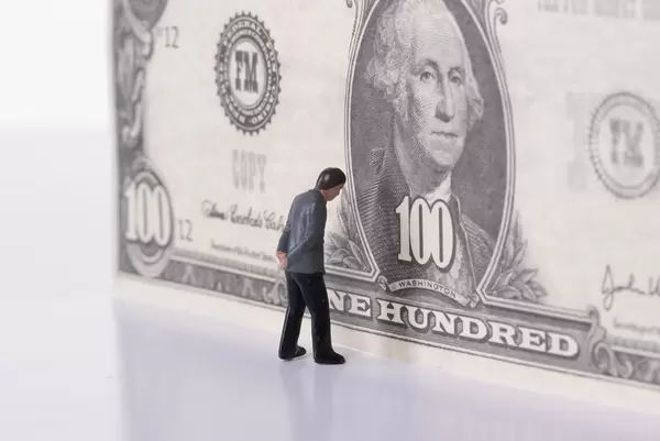 Miniature businessman standing in front of 100 dollar banknote. Paywall concept