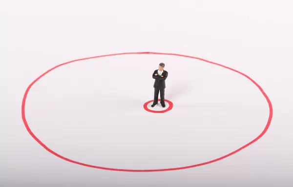 Miniature businessman standing in red circle