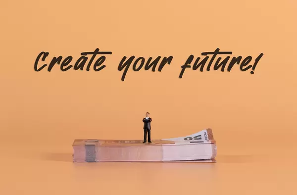 Miniature businessman standing on a stack of Euro money with Create your Future text