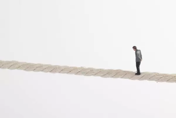 Miniature businessman standing on rope