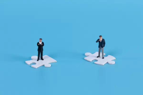 Miniature businessman standing on white jigsaw puzzle piece