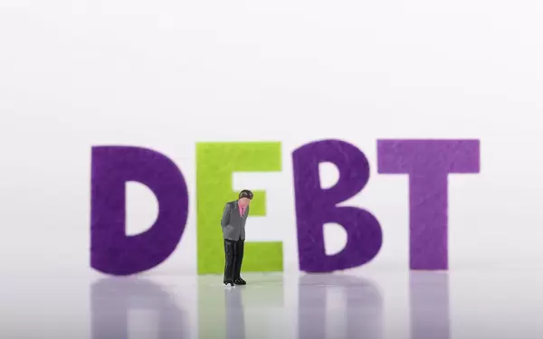 Miniature businessman with Debt text on white background