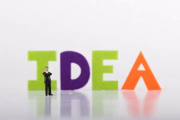 Miniature businessman with Idea text on white background