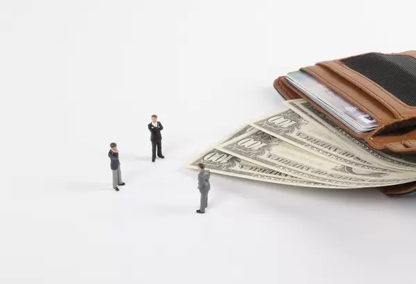 Miniature businessman with open wallet and Dollar banknotes