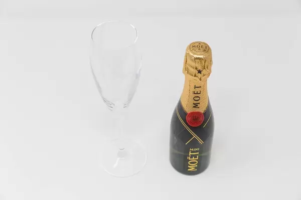 Miniature champagne: a bottle of Mini Moët with an empty champagne glass on a white background