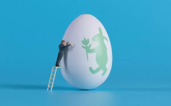 Miniature cleaner cleaning easter egg on blue background
