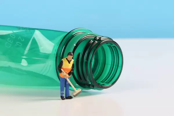 Miniature cleaning worker with empty plastic bottle