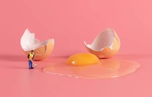 Miniature cleaning workers cleaning broken brown chicken egg