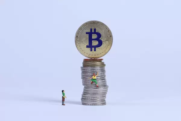Miniature climber climbing on coin stack to Bitcoin coin